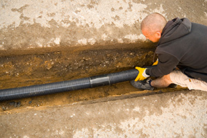 Man Fitting Piping Into The Ground