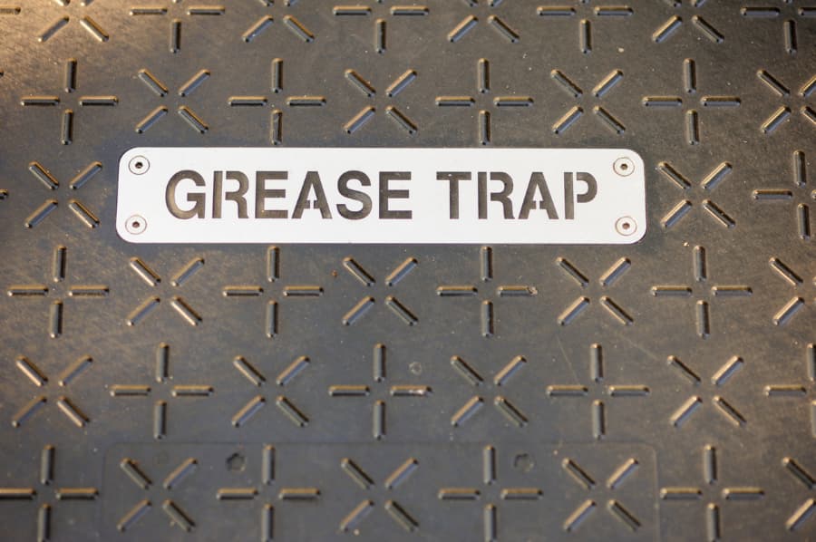 Stenciled metal grease trap sign on metal cover